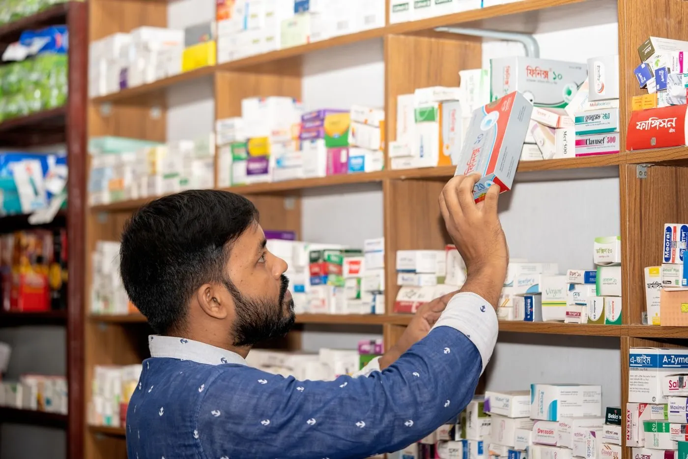 Pharmacist picking medicines from pharmacy shelves